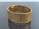 a close up of a gold bracelet on a black surface
