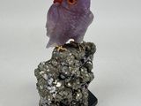 a purple bird sitting on top of a rock on a white surface