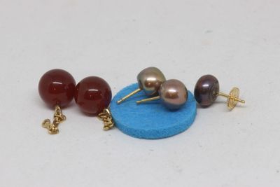 three pairs of earrings that are on a blue surface