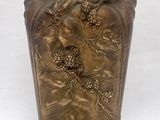 un vase en bronze posé sur une surface blanche