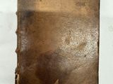 un vieux livre avec un trou au milieu, posé sur une surface blanche