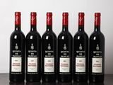 six bottles of red wine lined up on a wooden table