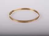 gros plan d'un bracelet en or sur une surface blanche