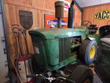 a green tractor parked in a garage with other vehicles