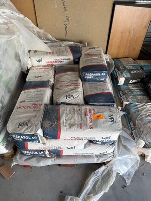 de nombreux sacs de ciment posés par terre à côté d'une pile de cartons