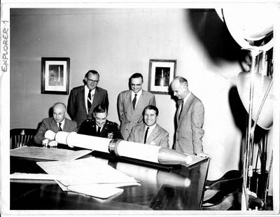 photographie en noir et blanc d'un groupe d'hommes assis autour d'une table