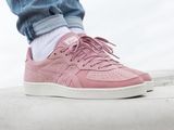 someone is standing on a ledge wearing pink sneakers and jeans