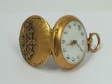 a gold pocket watch with a white face on it