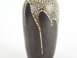 a black vase with a white and brown design on it