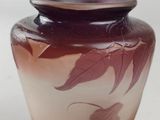 a purple vase with leaves on it sitting on a white surface