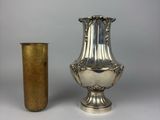 a silver vase next to a gold cup on a table