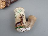 a small vase with a deer on it next to a broom