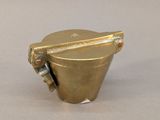 an image of a brass cup with a handle on a white surface