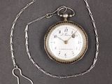a pocket watch with a chain around it on a table