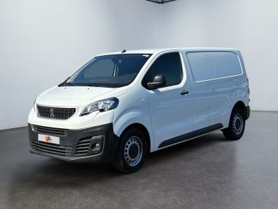 La petite camionnette blanche est garée dans une grande pièce.