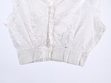 white cropped top with ruffles on a hanger against a white wall