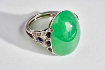 an image of a green jade and sapphire ring on a white surface