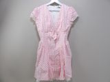 pink and white gingham dress hanging on a hanger against a gray wall