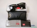 Des lunettes de soleil Ray-Ban et leur étui posés sur une table, à côté d'une paire de lunettes