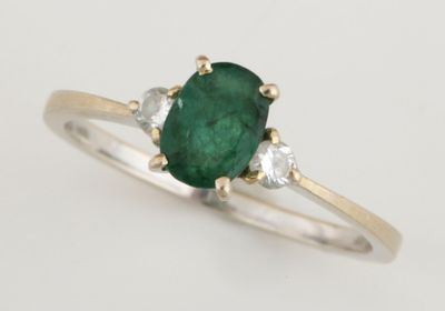 un gros plan sur une bague sertie d'une émeraude verte et de diamants