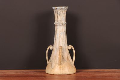 un vase blanc posé sur une table, avec un mur noir en arrière-plan