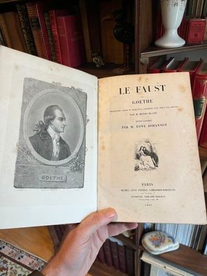 une personne tenant un livre à la main devant une bibliothèque