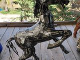 sculpture of a horse made out of scrap metal on a porch