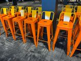 rows of orange metal bar stools lined up against a blue wall