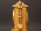 a gold clock sitting on a wooden table with a black background