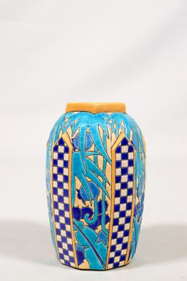 un vase bleu et jaune posé sur une surface blanche
