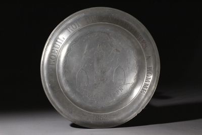 un vieux plat en argent posé sur une table, lui-même posée sur une autre table