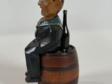 a figurine of a man sitting on top of a barrel