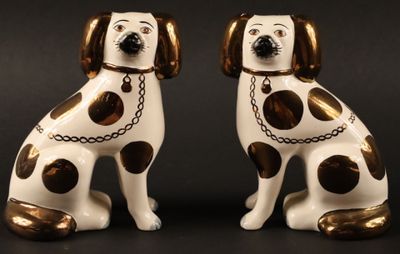 paire de figurines de chiens blanches et marron, avec des chaînes autour du cou