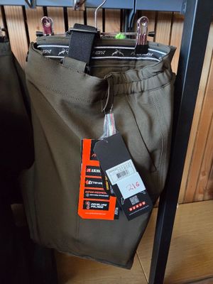 pants hanging on a rack in a clothing store with tags on them