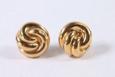 gros plan d'une paire de boucles d'oreilles en or sur une surface blanche