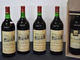 quatre bouteilles de vin sont alignées les unes à côté des autres près d'une caisse en bois