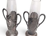two silver vases with handles on each of them