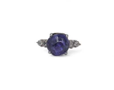 a close up of a purple sapphire and diamond ring on a white background