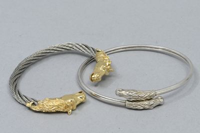 une paire de bracelets en argent et en or ornés de deux oiseaux