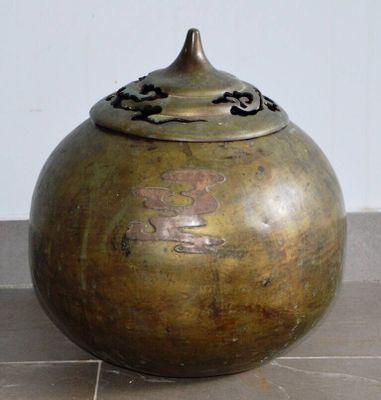 un grand vase en bronze posé sur un sol carrelé