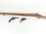 un vieux fusil en bois accompagné de deux revolvers, sur fond blanc