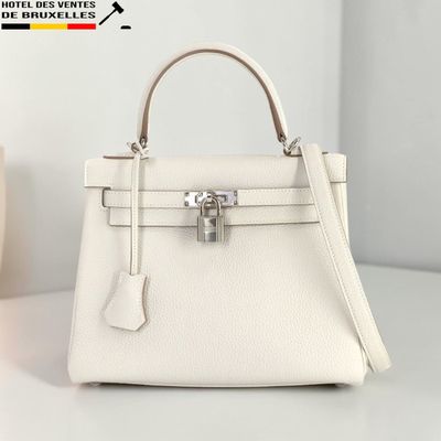un sac à main blanc posé sur une table, à côté d'un vase