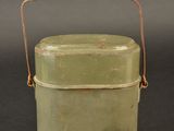 a small green container with a handle on a table