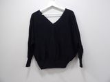 black v - neck sweater hanging on a hanger against a white wall