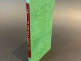 a green book sitting on top of a table next to a gray wall