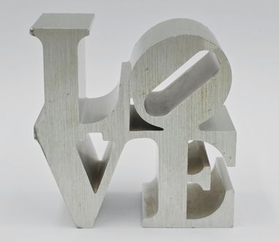 un gros plan d'une sculpture métallique représentant le mot « amour » sur fond blanc