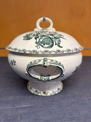 un saladier blanc et vert avec un couvercle posé sur une table