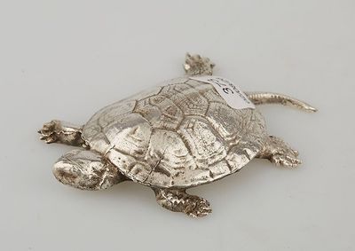 une tortue argentée posée sur une surface blanche
