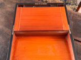 a small wooden box sitting on a table with a chair in the background