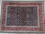 un tapis oriental posé au sol, avec une bordure noire et rouge